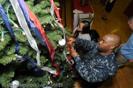 Interior Communications Electrician 2nd Class Kevin Penson places an ornament on the Commander, U.S. Naval Forces Japan tree dur